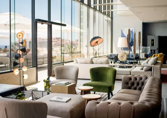 Room with large glass walls, looking out to an outdoor patio with white umbrellas