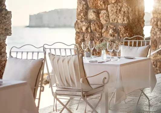 Outdoor patio with large stone pillars and white dining tables with wine glasses