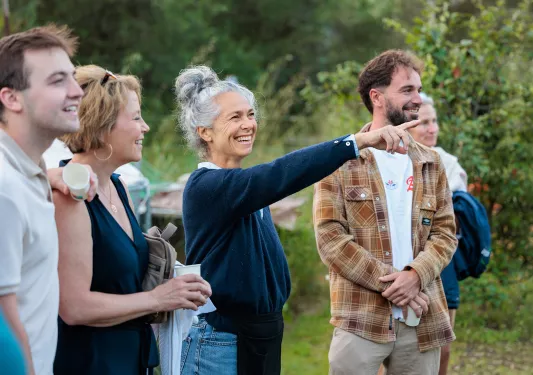 Group of people smiling while pointing to plants in a garden