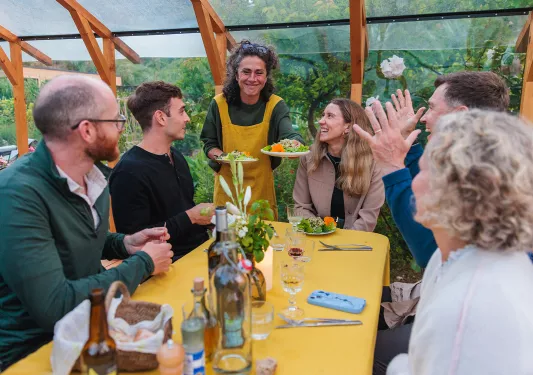 Group of people at a dining table with a waitress handing plates of food