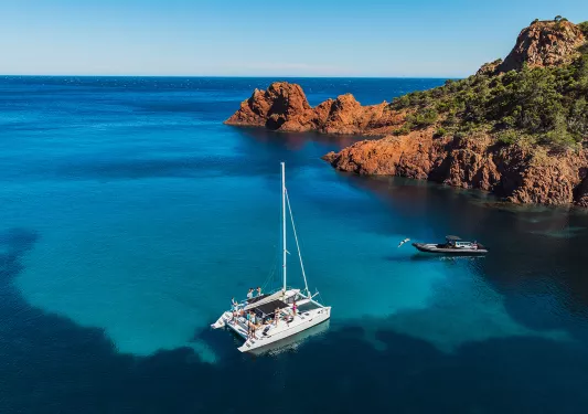 White boat in the ocean by large cliffs, with groups of people of the boat