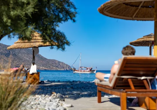 People sitting on reclining chairs by the shore of an ocean