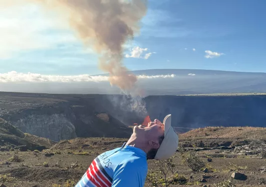 Man with his mouth open, with a geyser smoke in the background