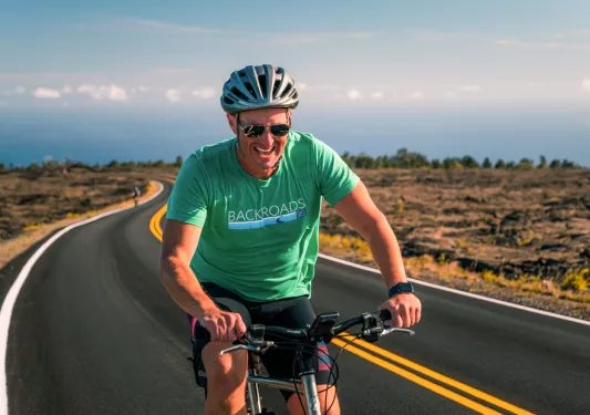 Man smiling while riding a bike on an empty road