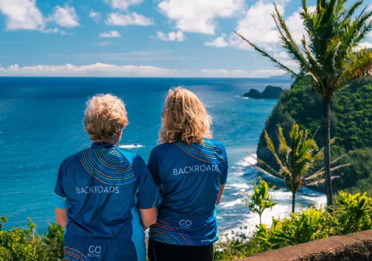 Two women wearing Backroads jerseys, looking out to the ocean