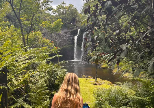 Woman walking towards a lake surrounded by tall plants