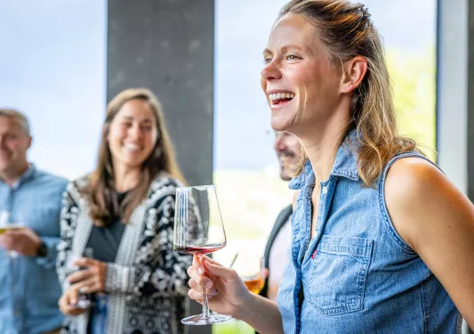 Group of people smiling while holding glasses of wine
