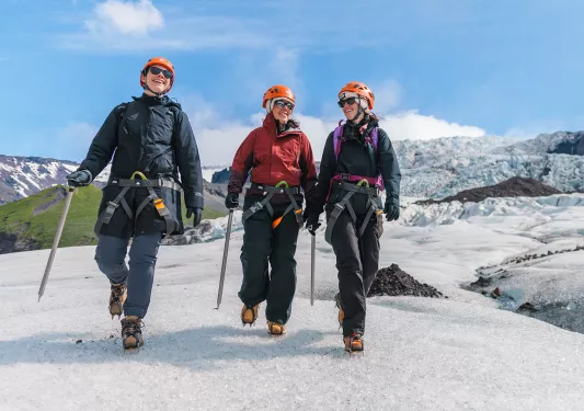 Three people wearing snow gear, walking through a icy trail