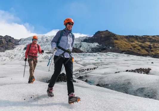 Two hikers walking through a snowy mounds on a trail