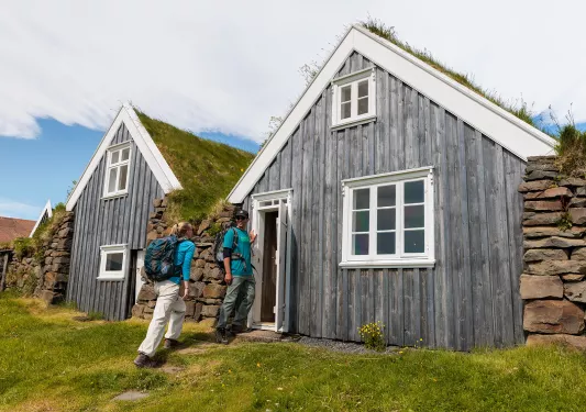 Man and woman smiling while entering a wooden cottage