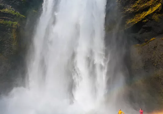 Large waterfall with two people walking on the ground level