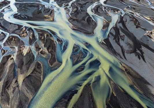 Large rivers of green water cutting through the sand at a beach