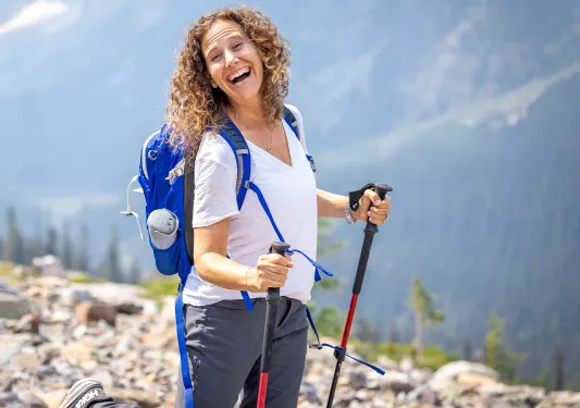 Woman smiling while walking a trail with hiking poles