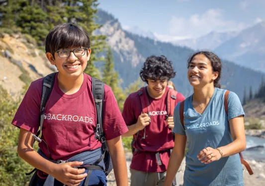 Group of three boys and one girl walking through a gravel trail
