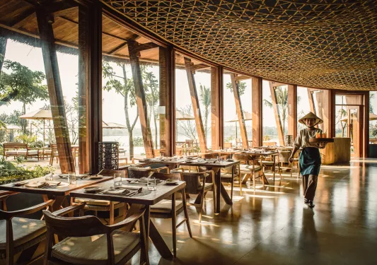 Woman wearing a straw hat, holding two drinks in a restaurant
