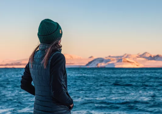 Woman wearing a beanie looking out towards a lake