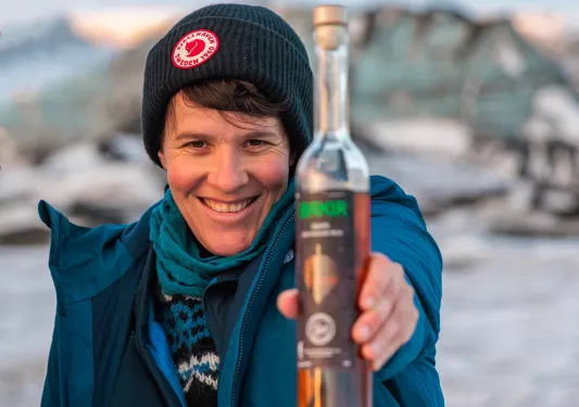 Woman wearing a beanie, holding up a bottle of olive oil