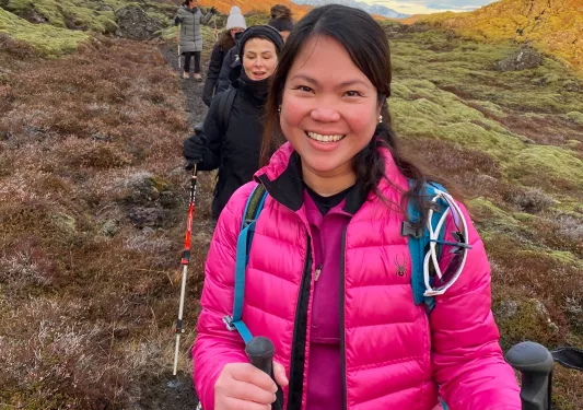 Woman in a pink jacket walking through a dirt trail