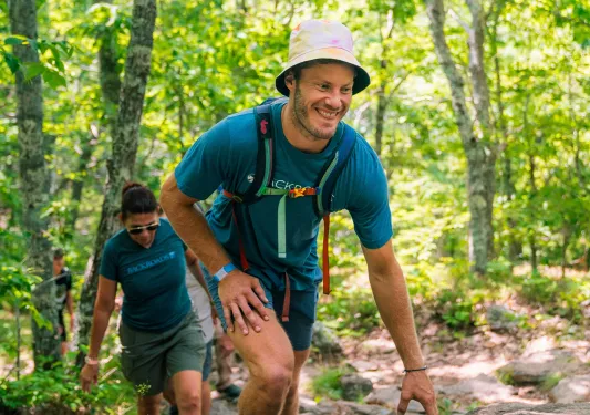 Man and woman smiling while ascending through a forest