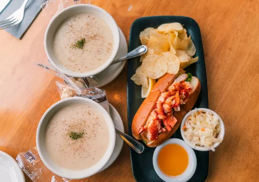 A lobster roll and two bowls of clam chowder