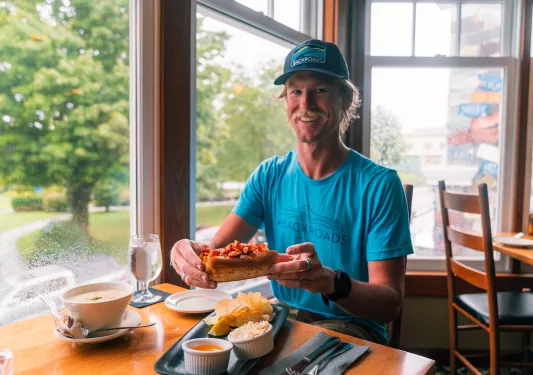 Man smiling while holding up a lobster roll