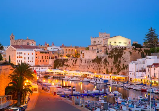 Row of boats on a river docked, with large buildings in the background