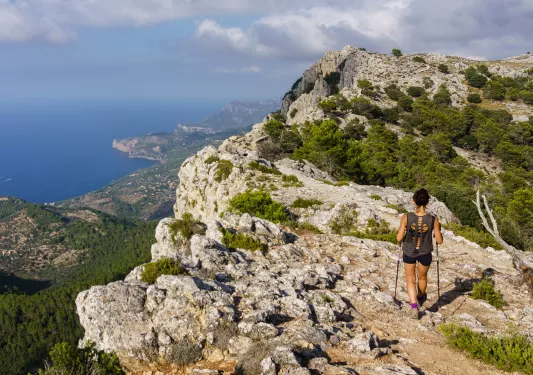 Woman with hiking poles, walking on a large mountain