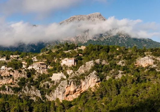 Large cliff with houses on top and foggy mountains in the distance