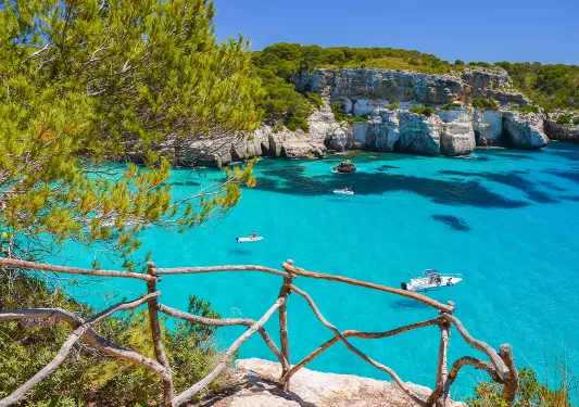 Stone path with view of clear blue water and boats floating in the ocean