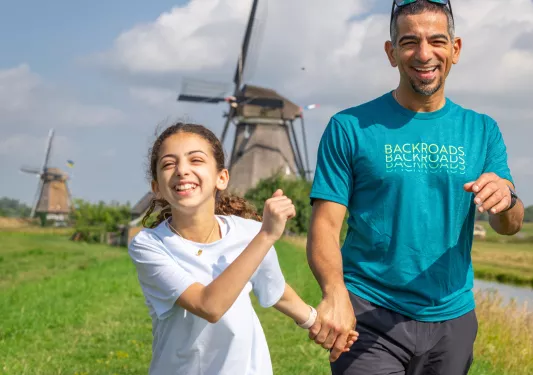 Man holding hands with his daughter, walking through a grassy field
