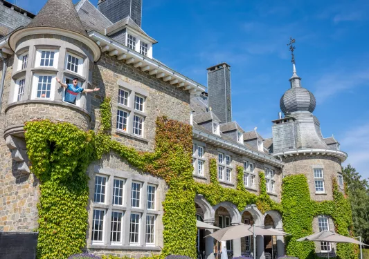 Exterior view of stone, castle-like building covered with large vines of leaves