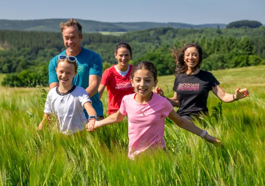 Group of kids running through a field of tall weeds