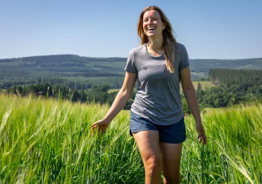 Woman smiling, while walking through a grassy field