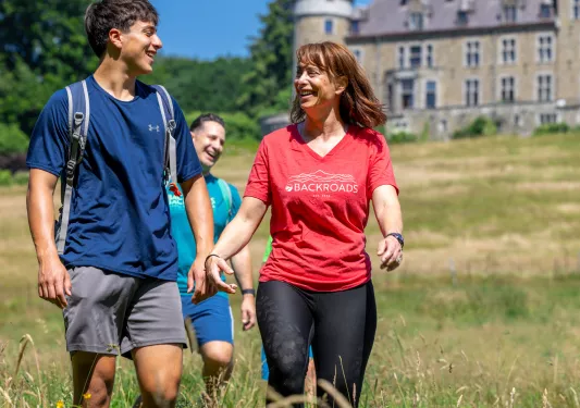 Man and woman walking through a grassy field with a castle-like building in the background