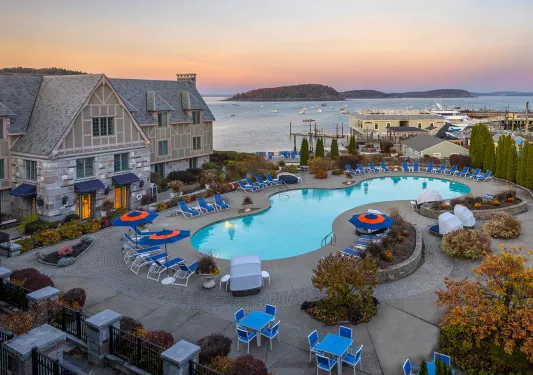 Outdoor pool, surrounded by blue reclining chairs and the ocean in the background