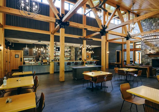 Restaurant and bar with wooden tables along the walls and large wooden pillars