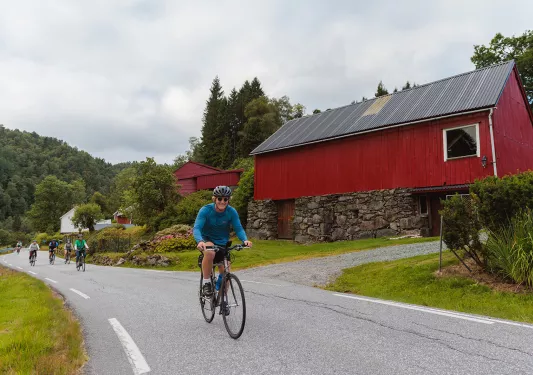 Man wearing a blue shirt, biking next to red buildings