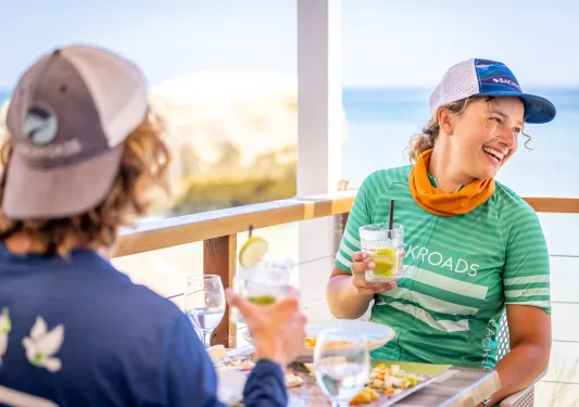 Woman smiling while holding up a glass, sitting outside on a patio