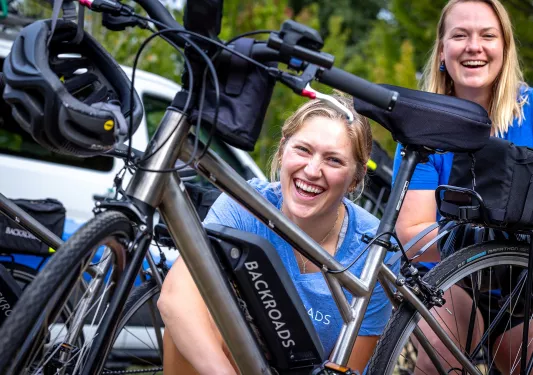 Two women smiling while standing next to an e-bike