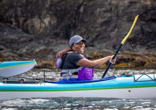 Woman smiling while paddling on a kayak