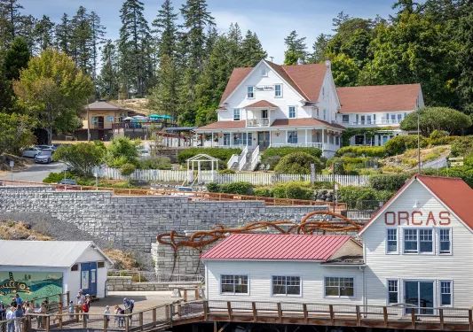 Exterior view of white buildings with orange roofs, and an ocean dock on sea level