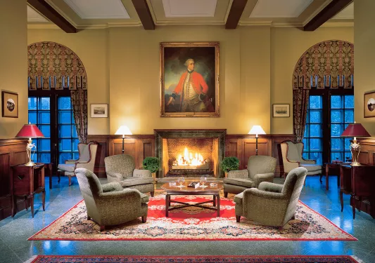 Hotel lobby, with cushioned chairs in front of a lit fireplace