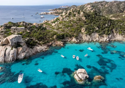 Large lake with boats floating, with views of the ocean and cliffs in the background