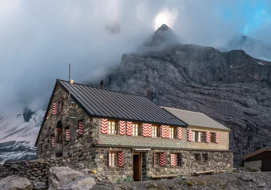 Exterior view of stone and brick building with a fog-covered mountain in the background
