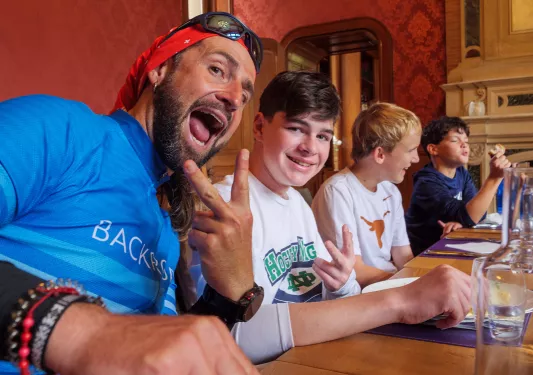 Man smiling and holding up a peace sign, with a younger teen next to him