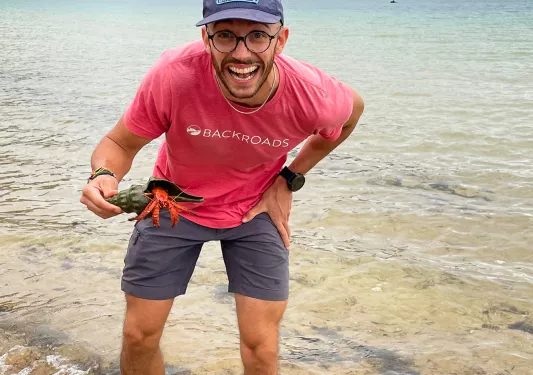 Man holding a seashell while standing in the ocean