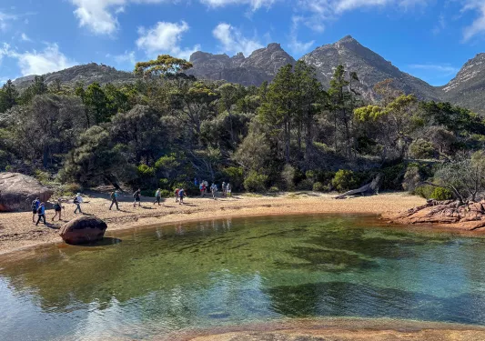 Group of people walking around a lake in the middle of a valley