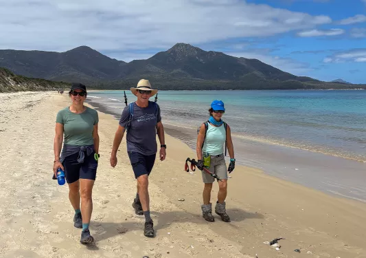 Man and two women walking along a beach