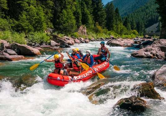 Group of people on a red raft, paddling 