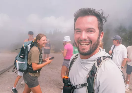 Group of people smiling while walking through a foggy trail